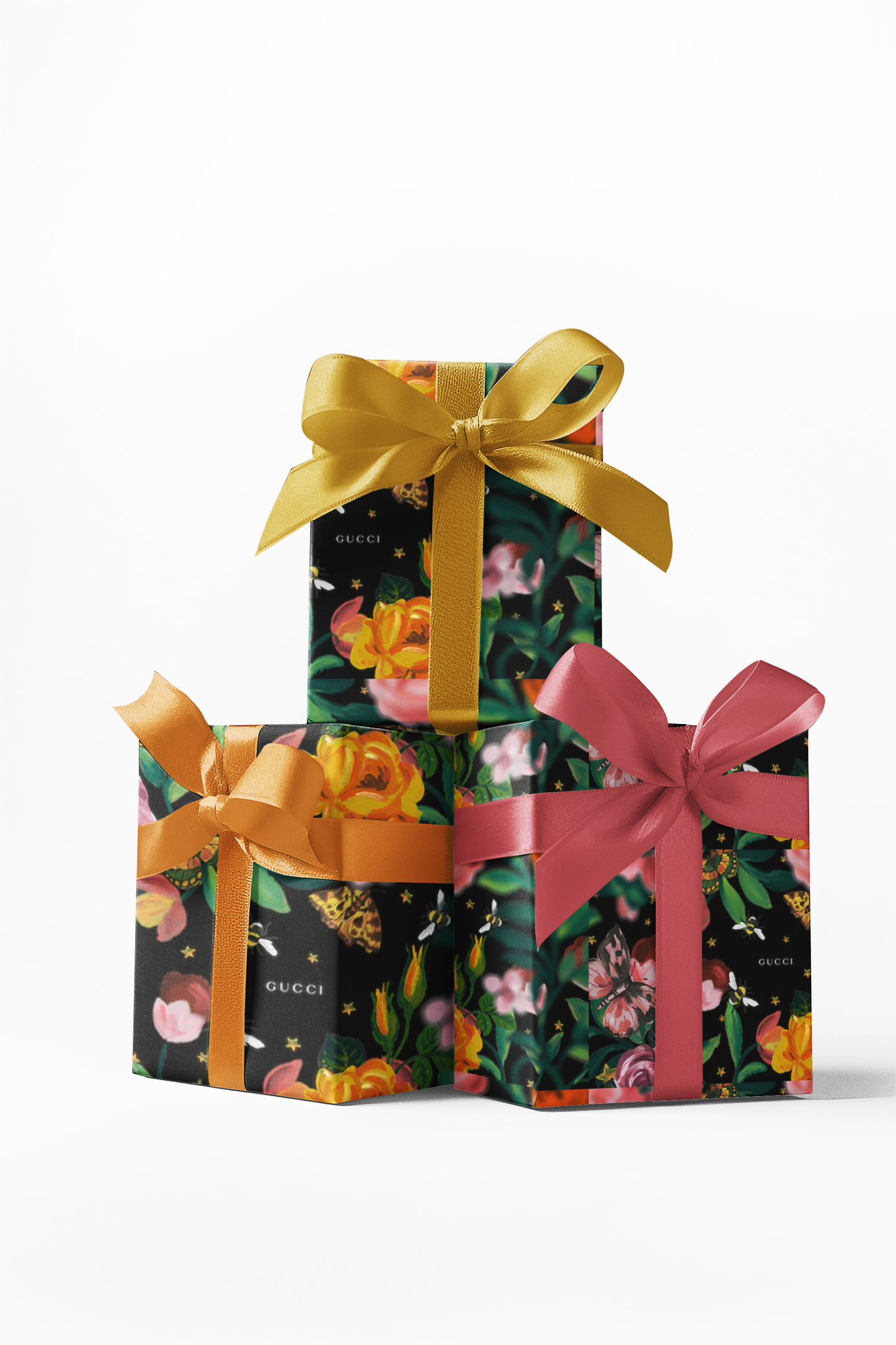 Stacked gift boxes wrapped in custom floral pattern wrapping paper with a golden bow on the top box.