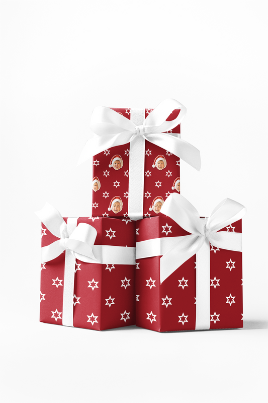 Stack of three red gift boxes with white stars and snowflake patterns, wrapped with white ribbon bows.