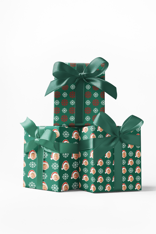 Stack of three wrapped gifts with green ribbon bows on top, featuring a custom wrapping paper with a red and white snowflake pattern.