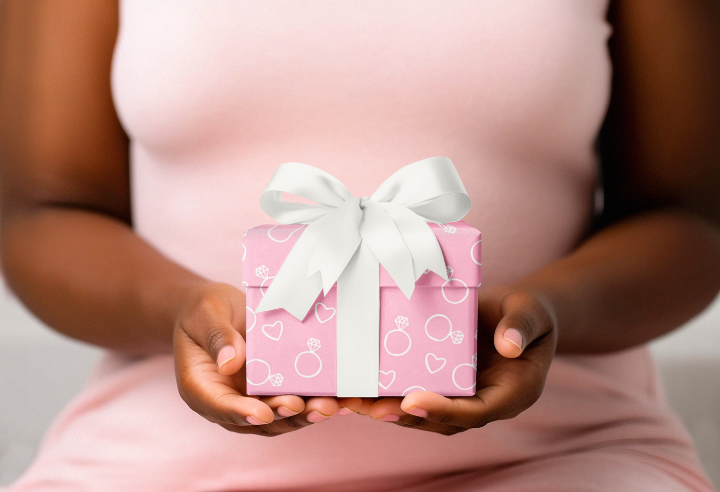 Person holding a pink gift box with a white bow