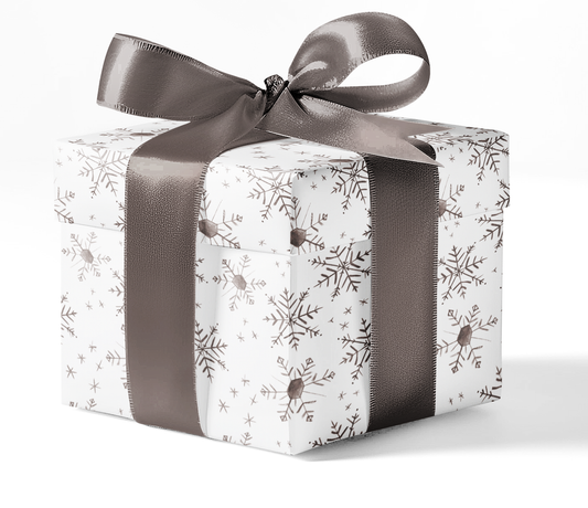 A gift box wrapped in custom wrapping paper with a snowflake pattern and tied with a gray ribbon.