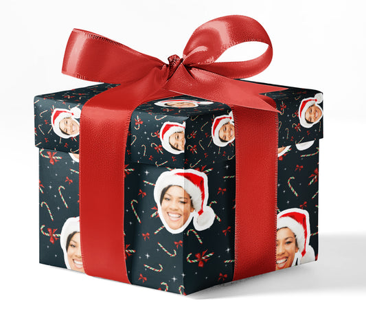 A gift box wrapped in custom wrapping paper with a pattern of candy canes and Santa hats, tied with a red ribbon.