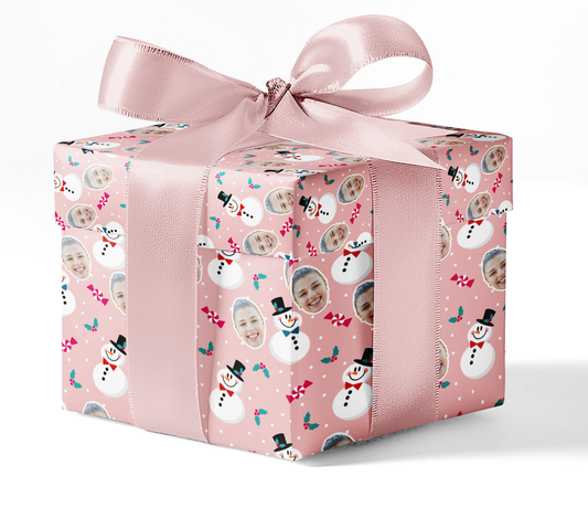 A gift wrapped in custom wrapping paper with a snowman pattern, adorned with a pink ribbon.