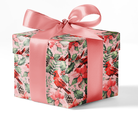 A gift box wrapped in custom wrapping paper with a red and green floral pattern, including images of cardinals, and tied with a pink ribbon.