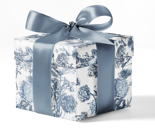 A gift box wrapped in custom blue toile print wrapping paper with a blue ribbon.