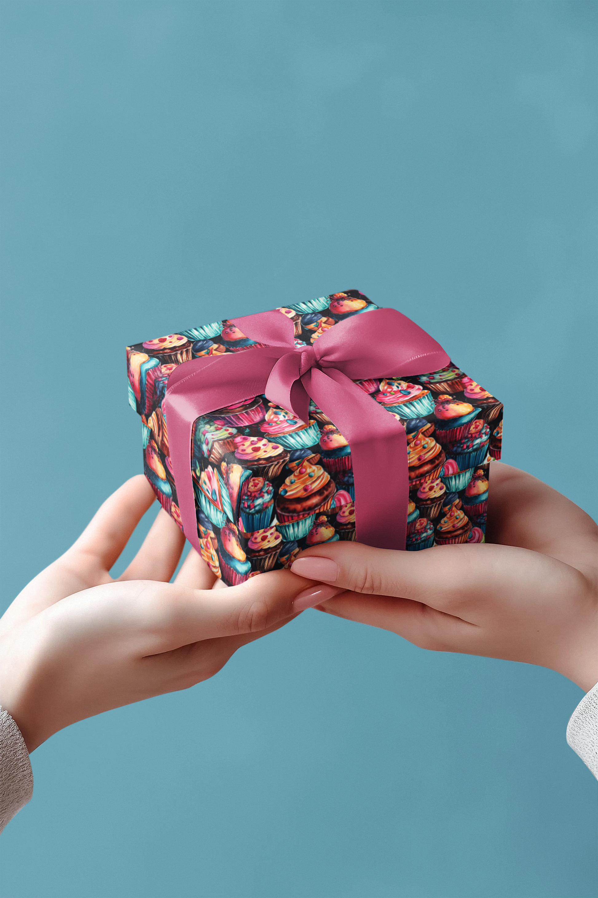 Two hands holding a small gift box with a colorful pattern and pink ribbon against a blue background