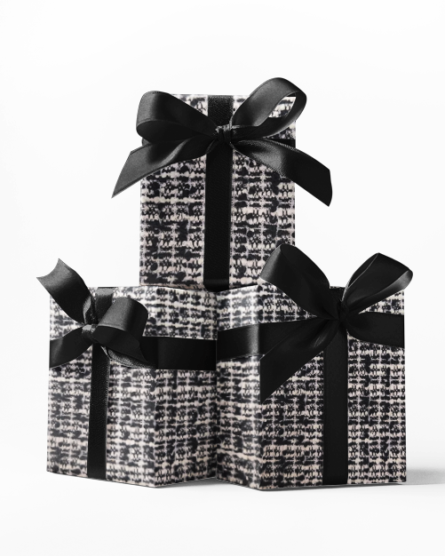 Stacked black gift boxes with a fabric wrapping paper featuring a geometric pattern and tied with black ribbons.