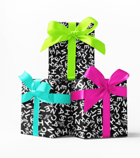 Three wrapped gifts with black and white text patterned wrapping paper and colorful ribbons in green, blue, and pink.