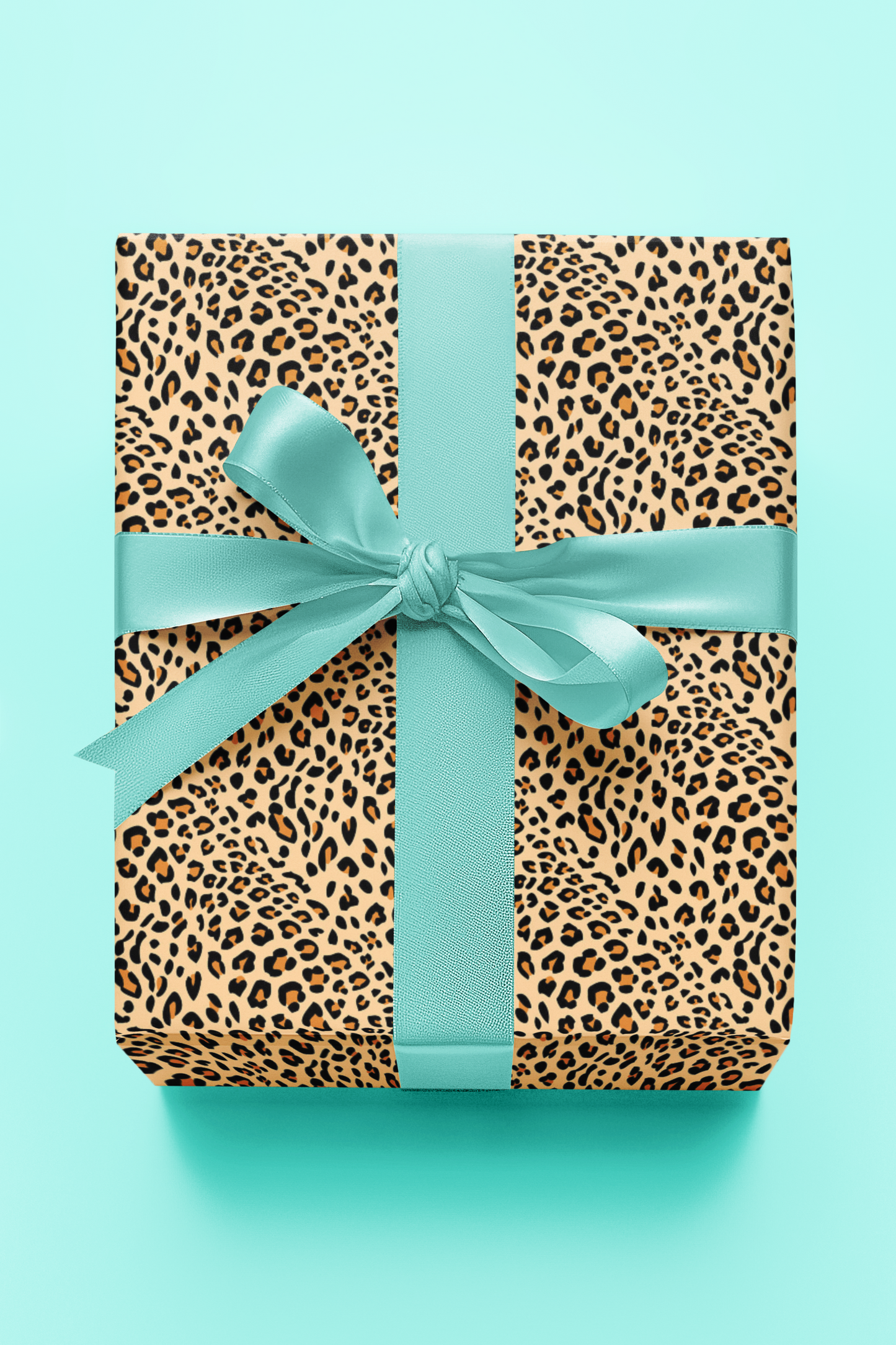 Gift box with leopard print pattern and teal ribbon on a light blue background