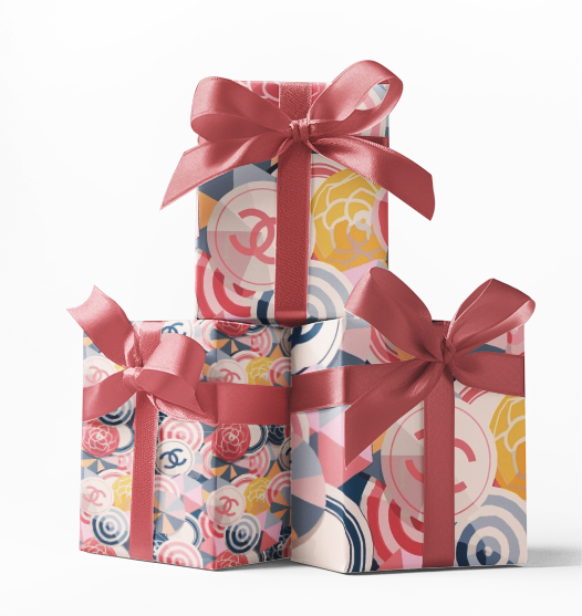 Stacked gift boxes wrapped in custom wrapping paper with a floral and geometric pattern design, tied with a red ribbon.