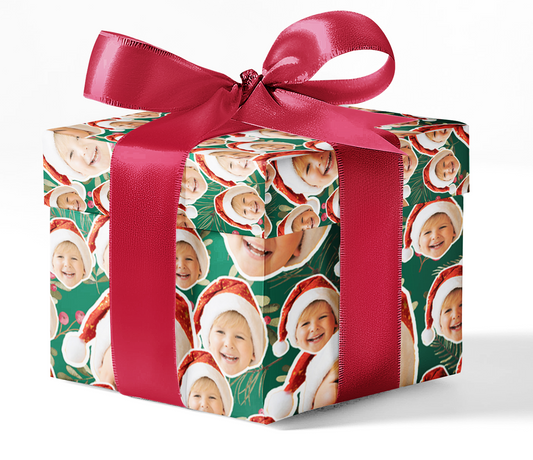A wrapped gift box with custom face Christmas wrapping paper and a red ribbon.
