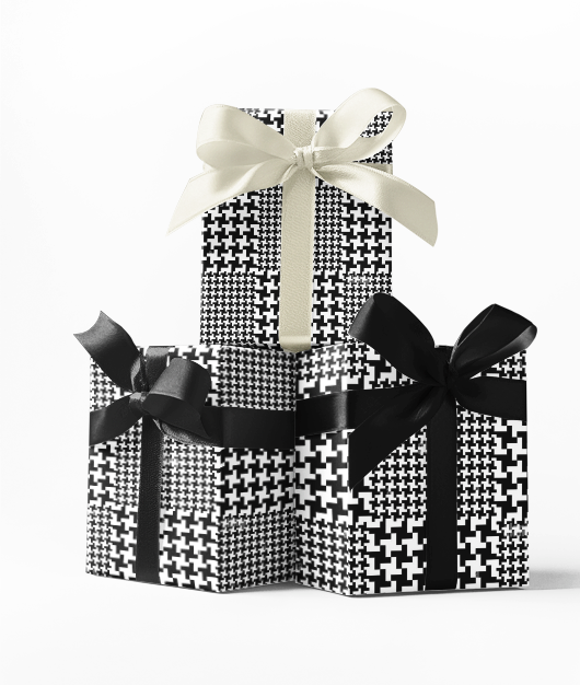 Stacked gift boxes wrapped in black and white houndstooth plaid print wrapping paper, tied with a ribbon bow.