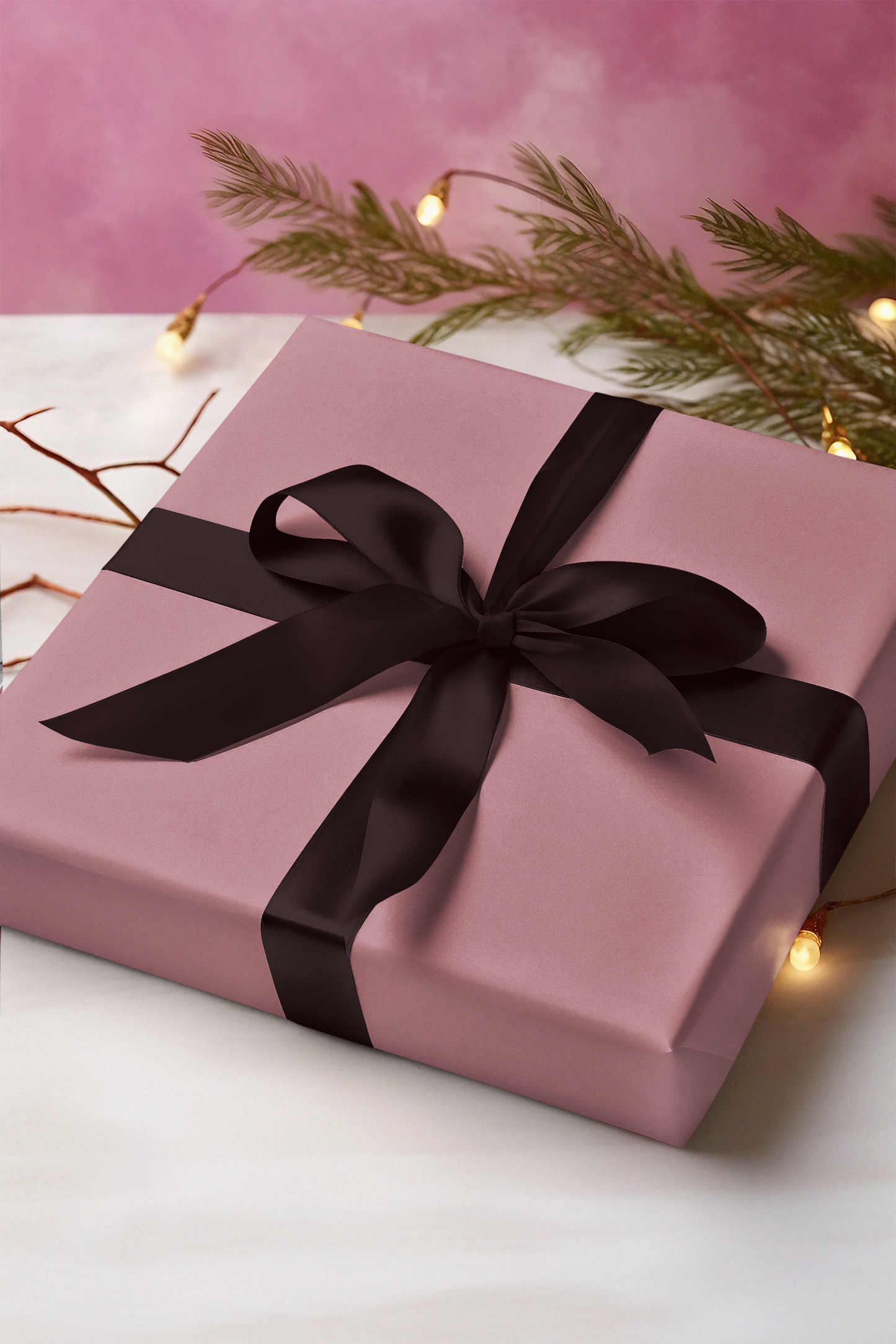 Pink gift box with a black ribbon on a white surface with a pink background