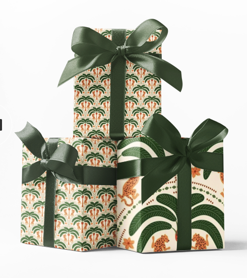Stacked gift boxes wrapped in green and beige patterned wrapping paper with a large green ribbon bow on top.