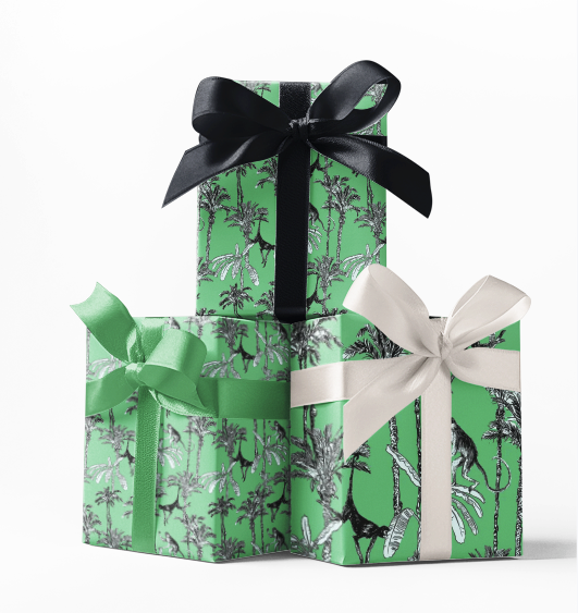 Three wrapped gifts with green wrapping paper featuring a black and white monkey pattern, tied with black, white, and green ribbons.
