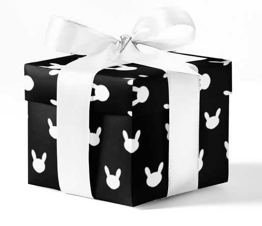 A gift box wrapped in black and white custom wrapping paper with bunny patterns, tied with a white ribbon.