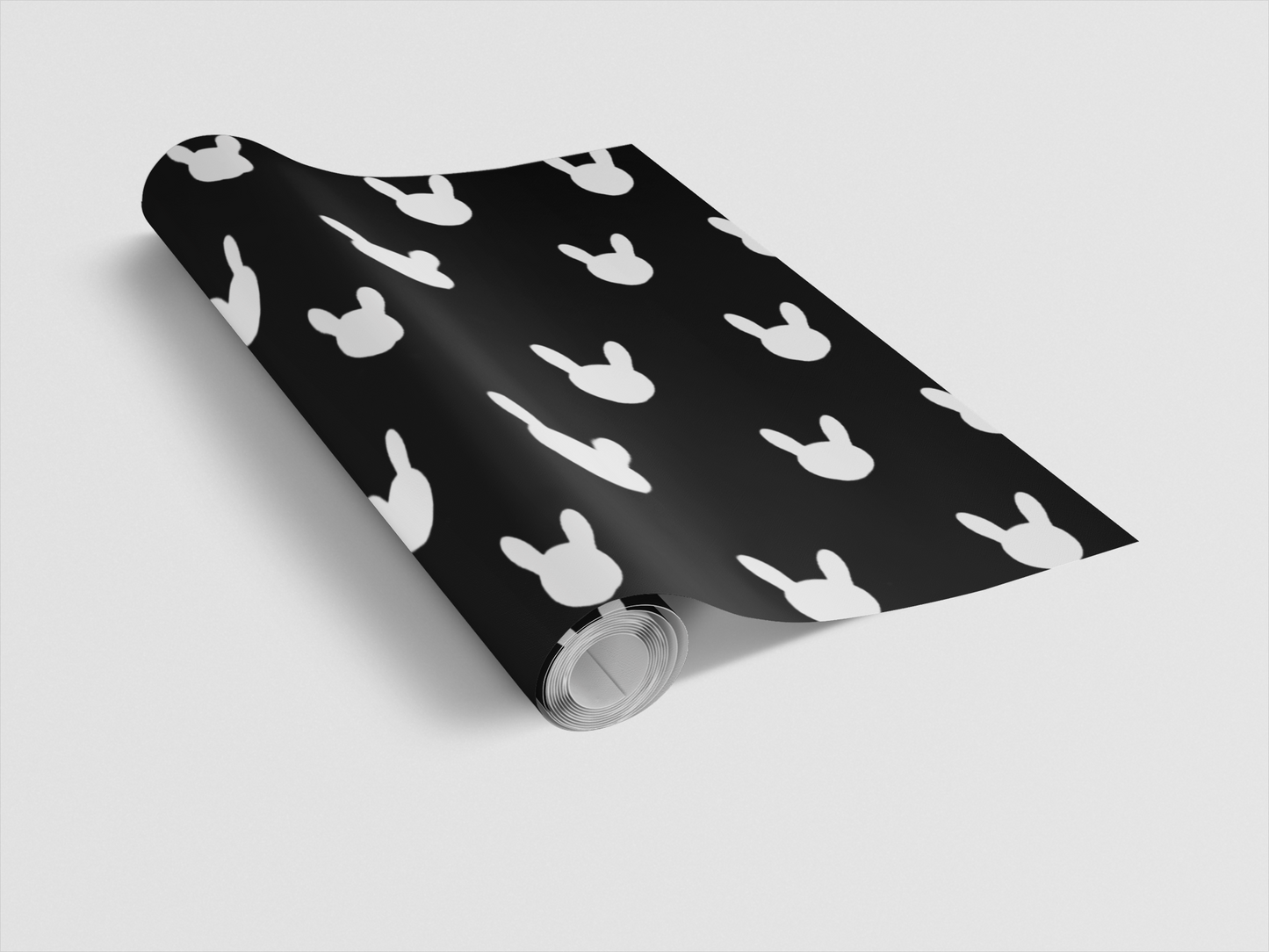 Roll of black wrapping paper with white mouse ears pattern on a light gray background