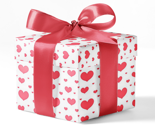 A gift box wrapped in white wrapping paper with a red heart pattern and tied with a red ribbon.