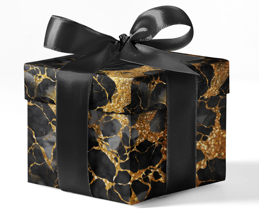 A gift box wrapped in black and gold marble patterned wrapping paper with a black ribbon.