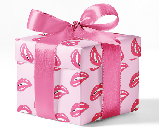 A gift box wrapped in pink wrapping paper with a lips pattern and tied with a pink ribbon.