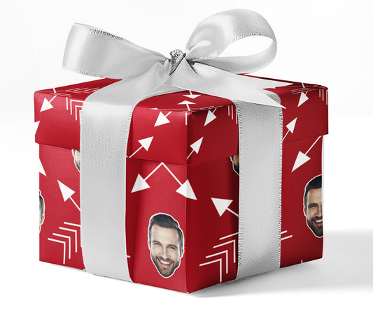 A gift wrapped in custom wrapping paper with a red and white arrow pattern, featuring a photo of a person, presented with a silver ribbon.