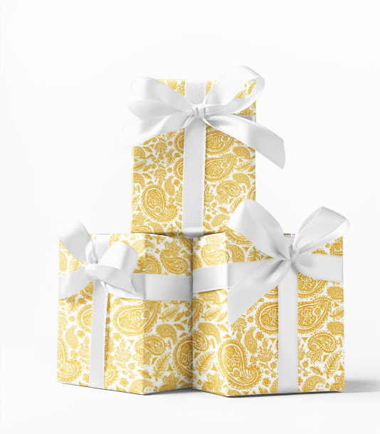 Three stacked gift boxes with yellow paisley pattern and white ribbons on a white background